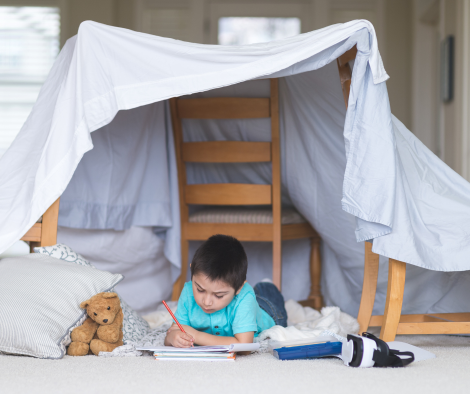Child reading under a white sheet fort, with teddy bears on the floor