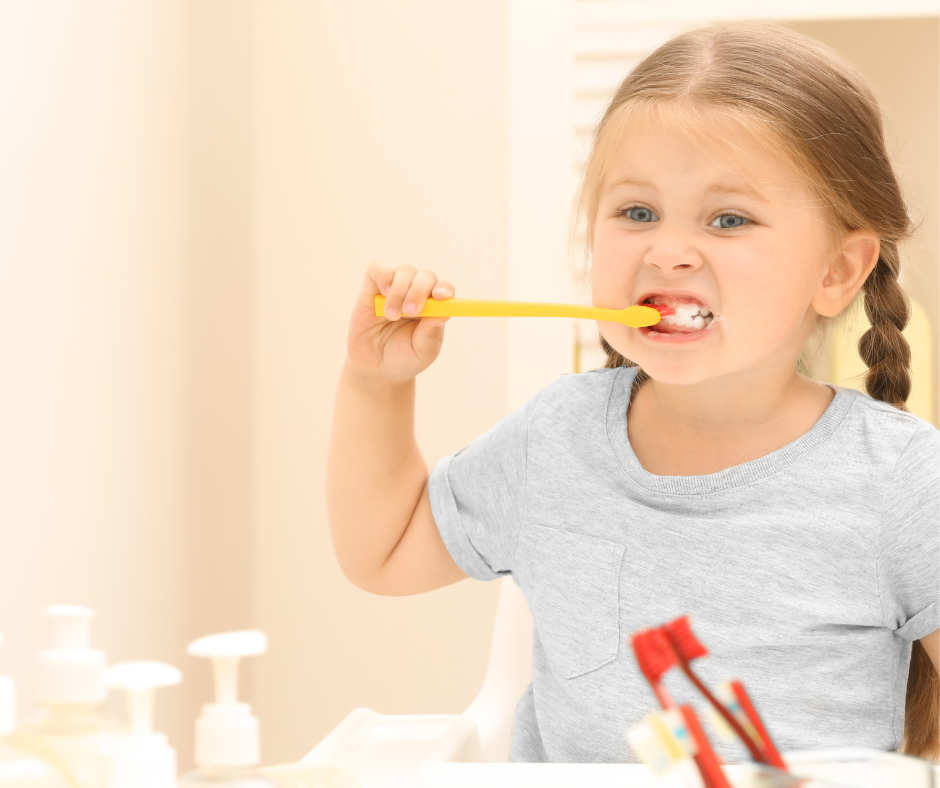 Child brushing teeth with a yellow toothbrush in a bright bathroom.