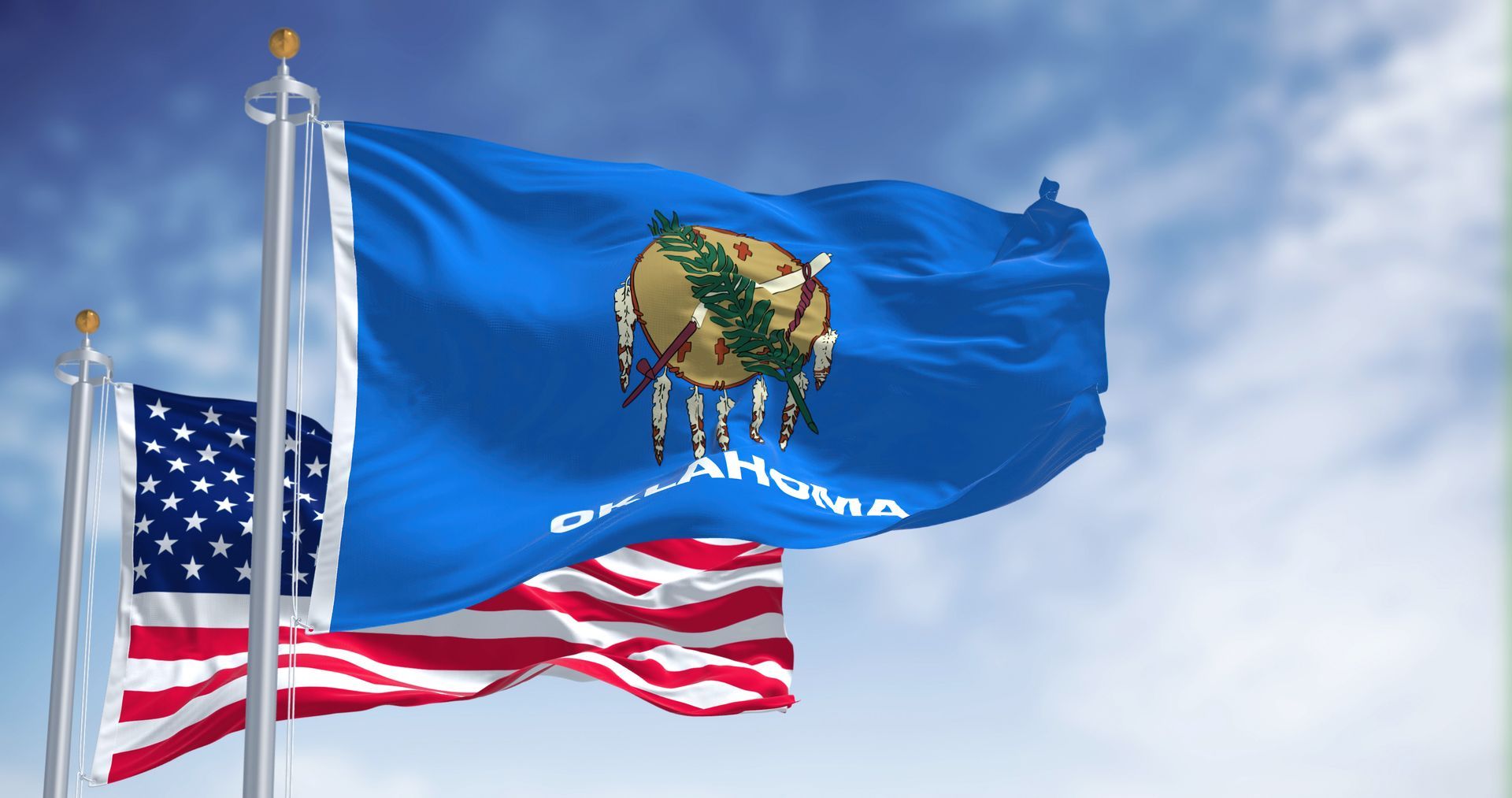An american flag and an oklahoma flag are waving in the wind