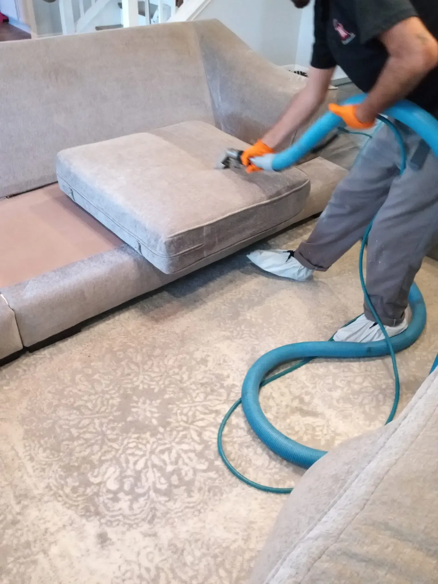 MB Carpet Cleaning- A man is cleaning a couch with a vacuum cleaner.