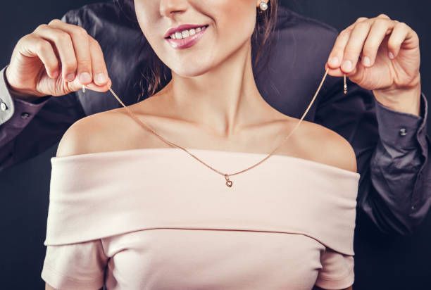 someone putting necklace on woman