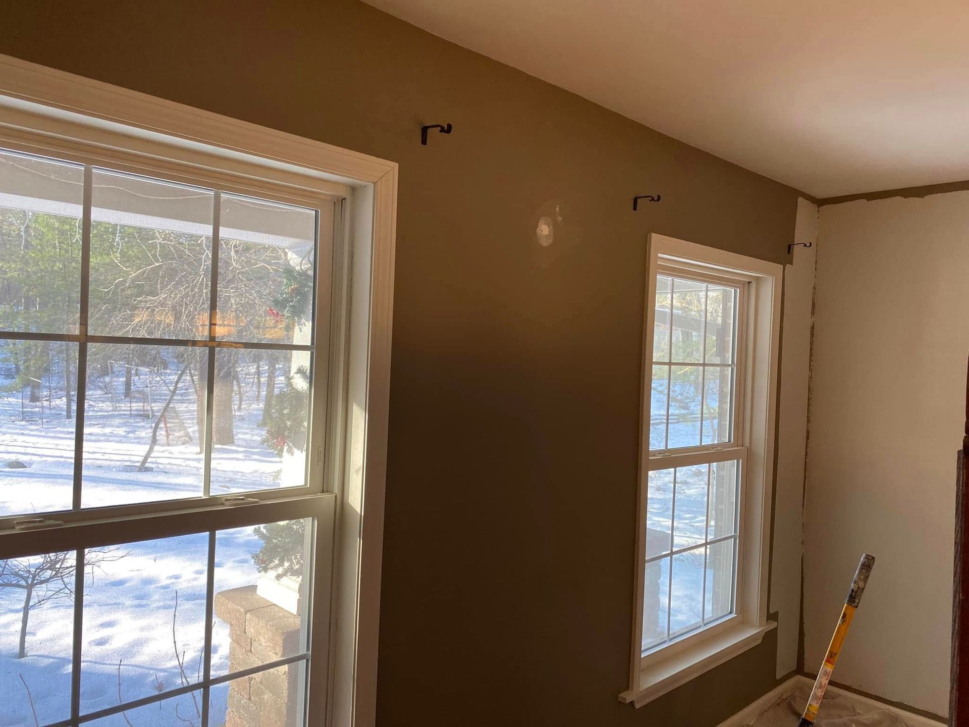 A room with two windows and a ladder in it.