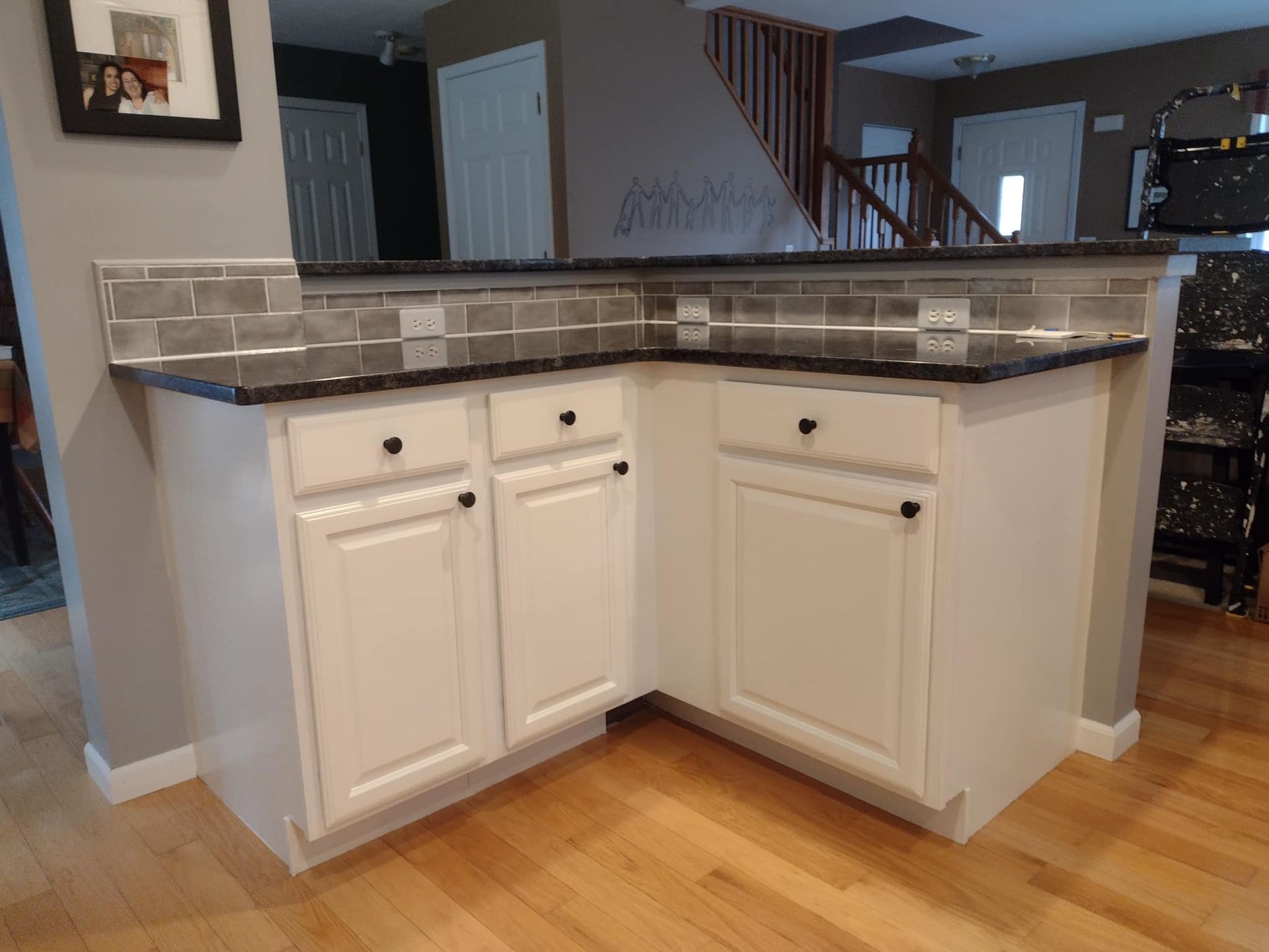A kitchen with white cabinets and a black counter top