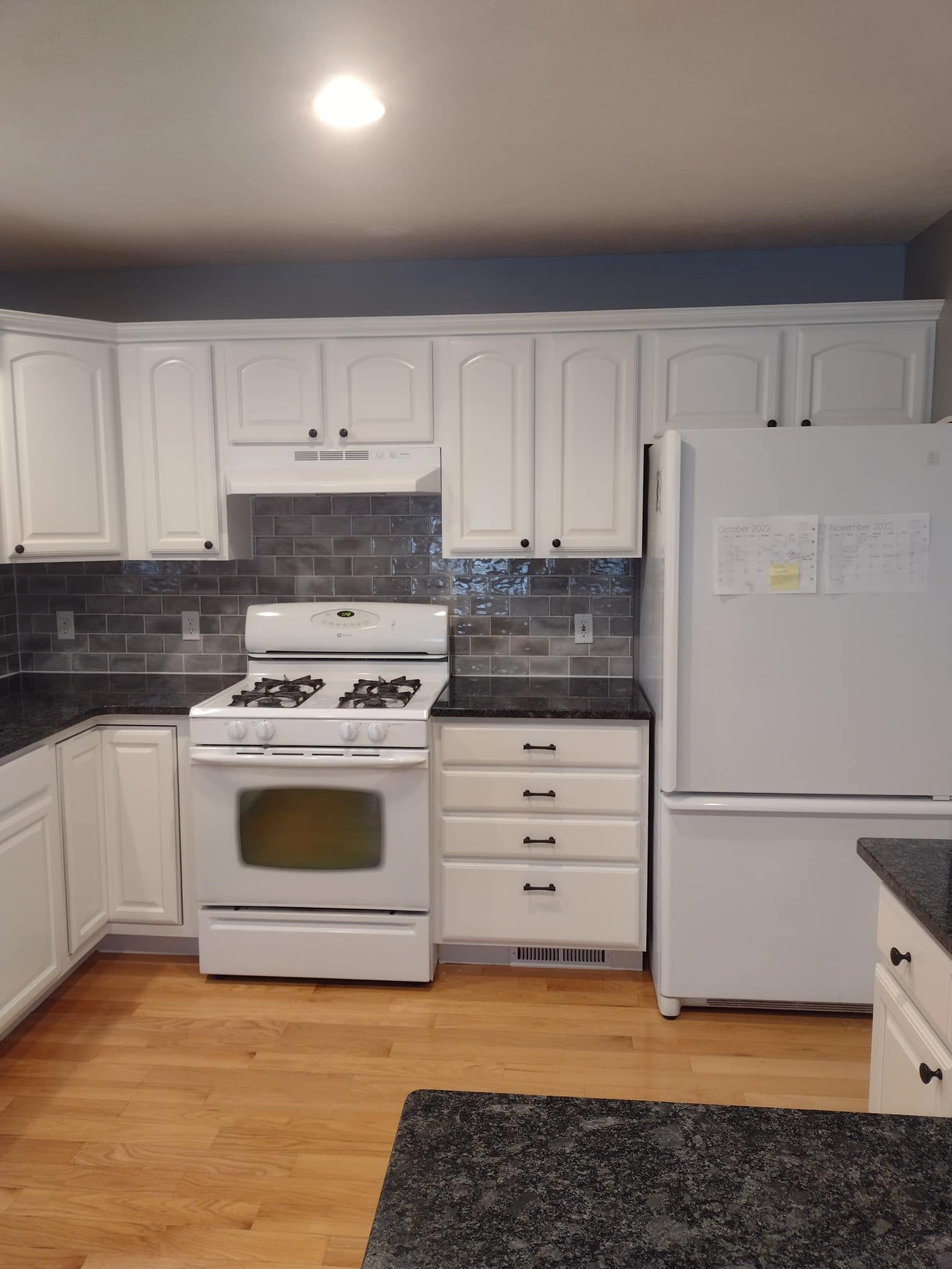 A kitchen with white cabinets , a stove and a refrigerator