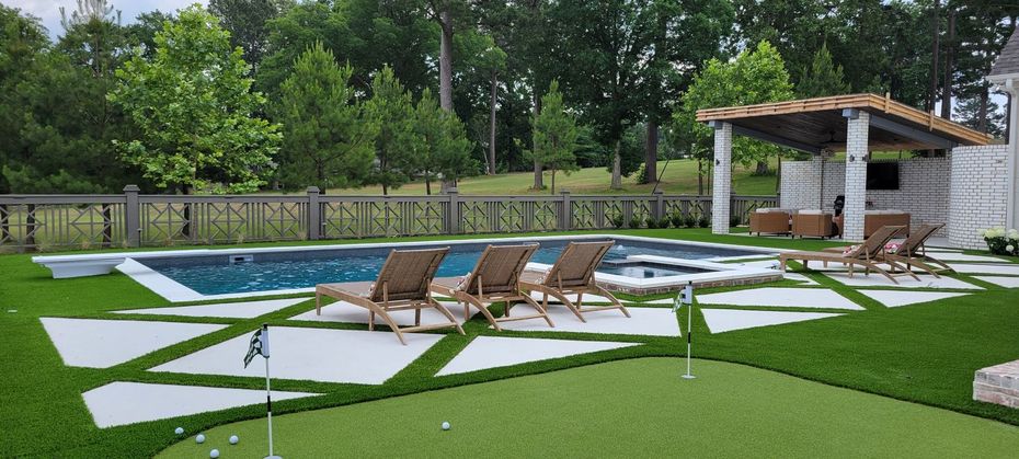 A large backyard with a swimming pool and a putting green.