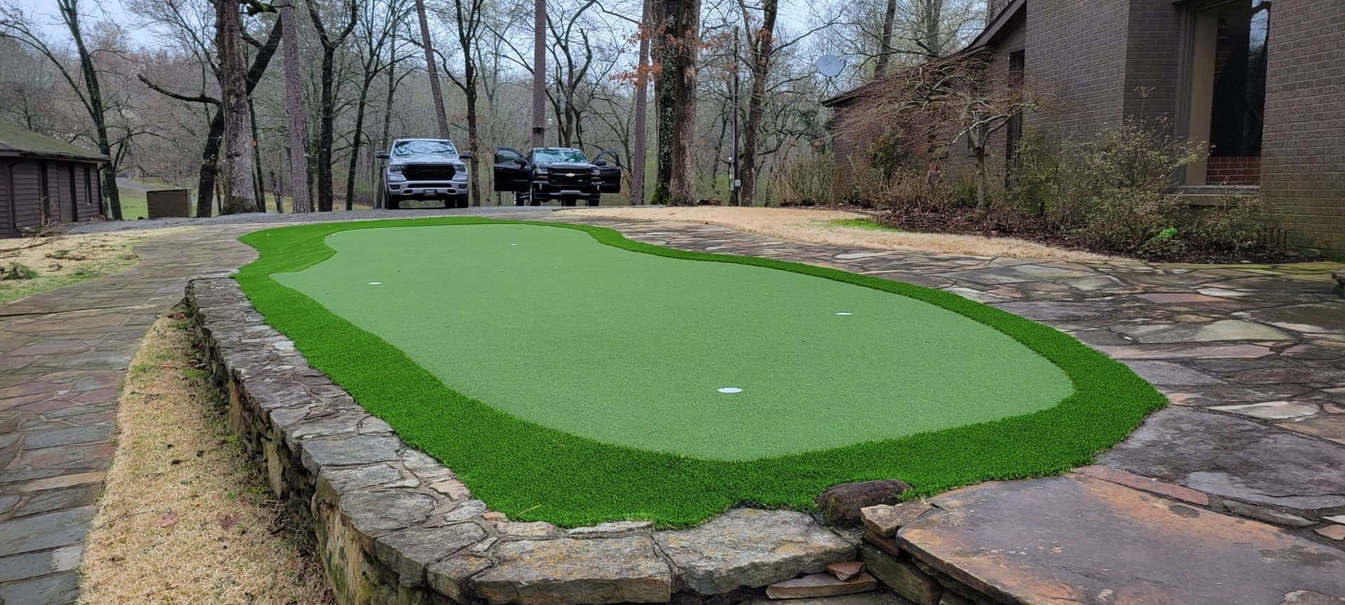 A car is parked on the side of the road next to a putting green.