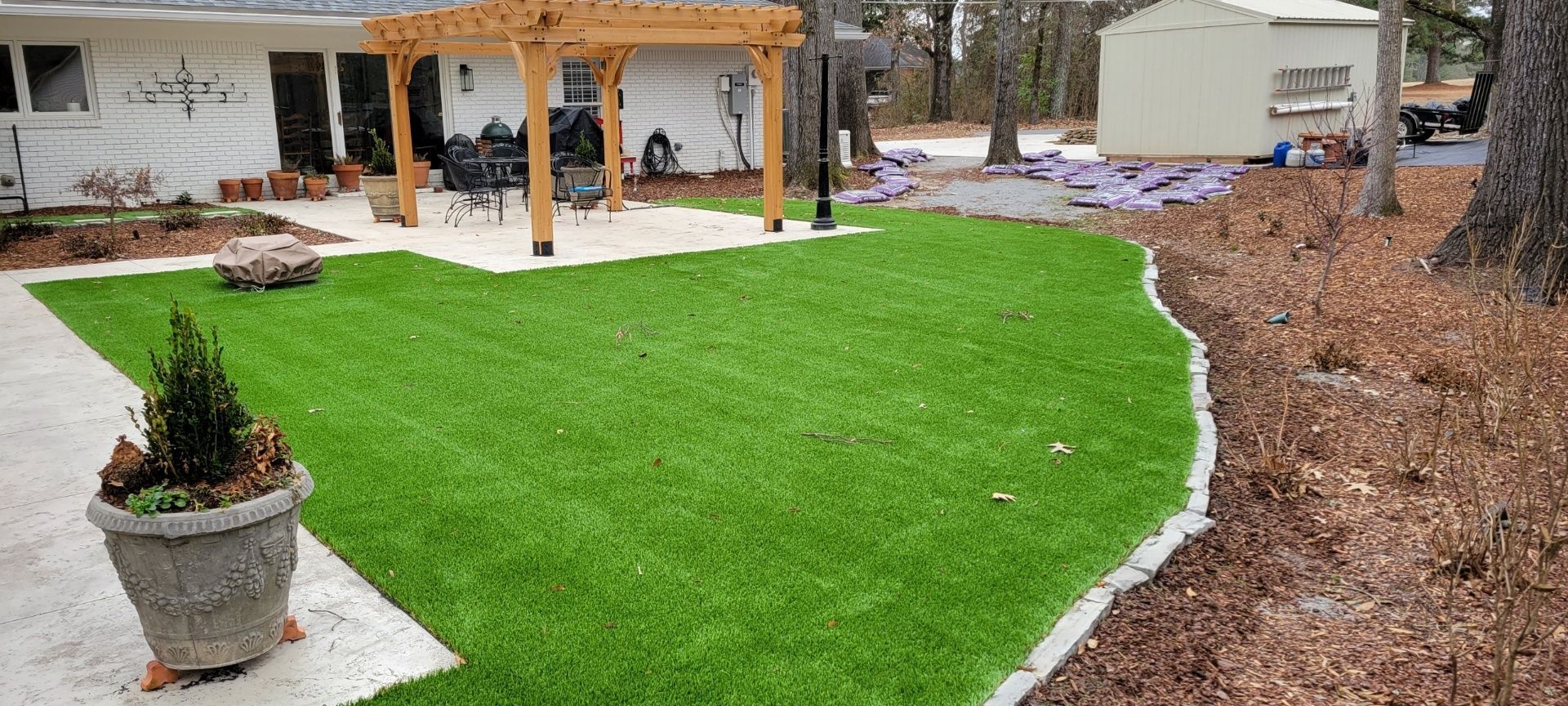 A backyard with a lush green lawn and a pergola.