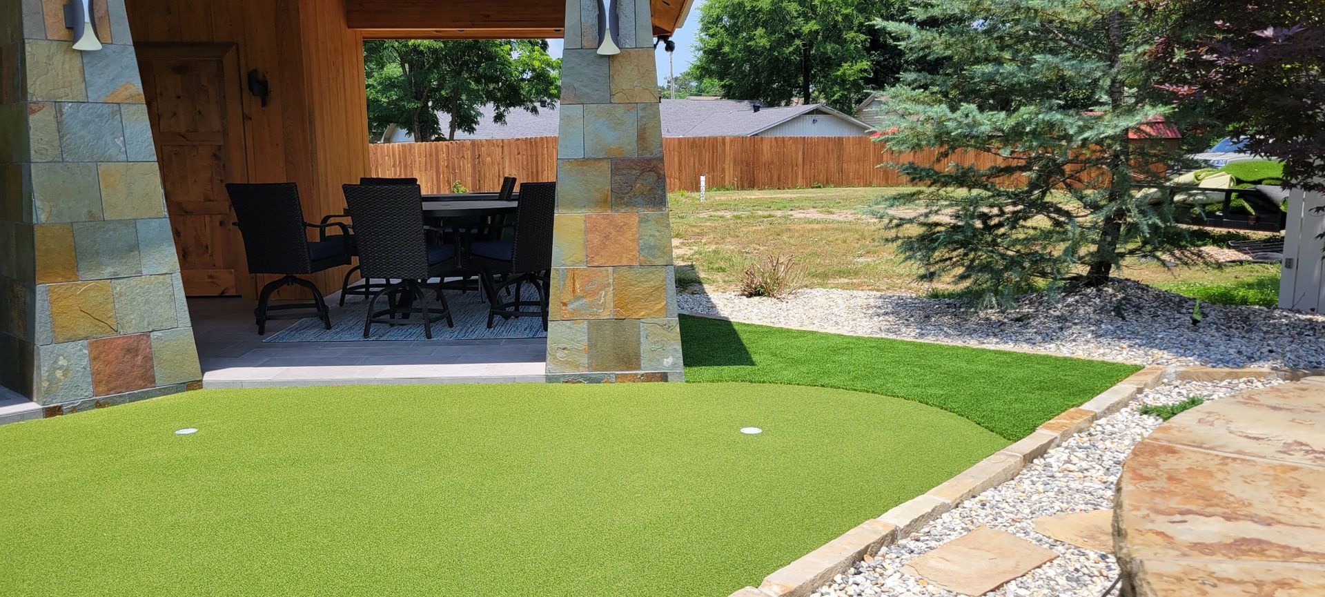 There is a putting green in the backyard of a house.