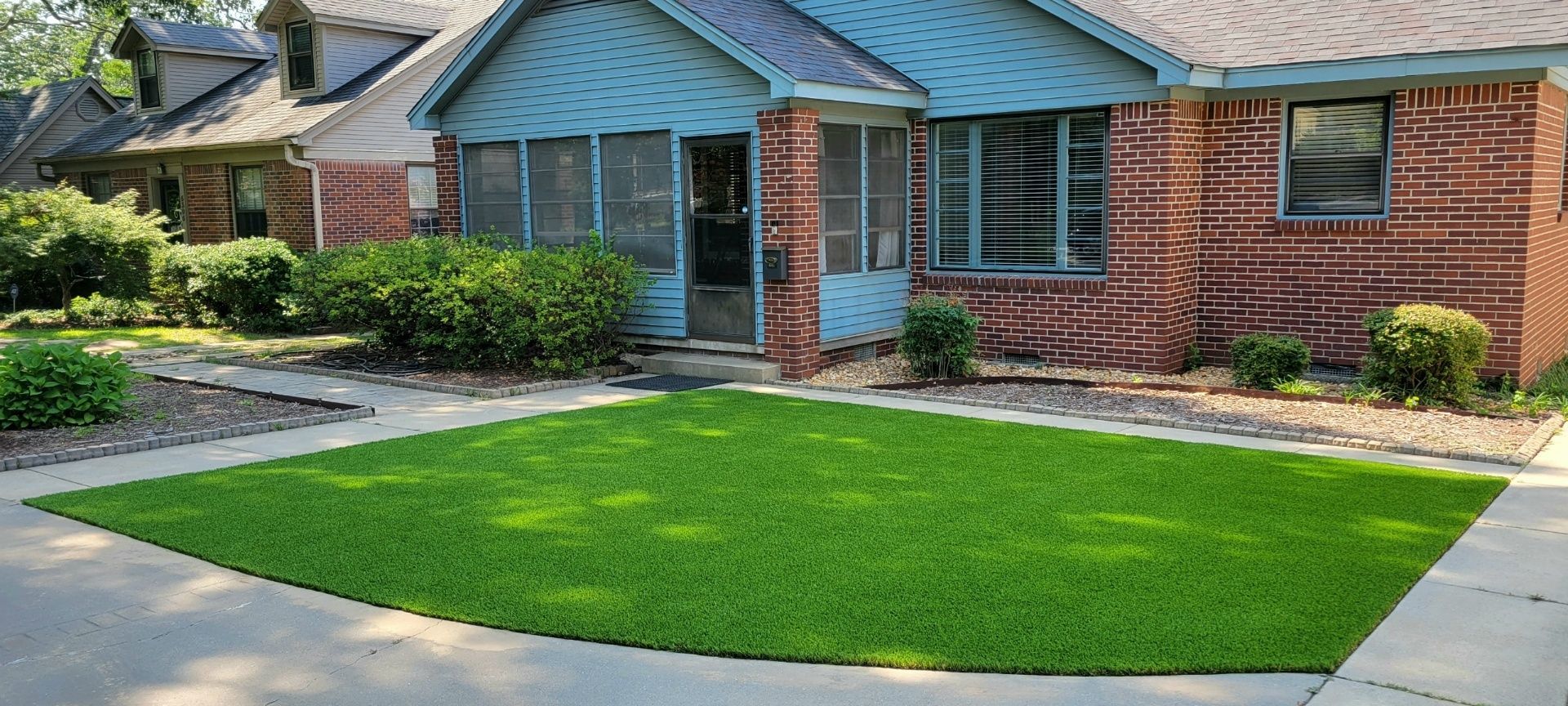 A brick house with a large lawn in front of it.