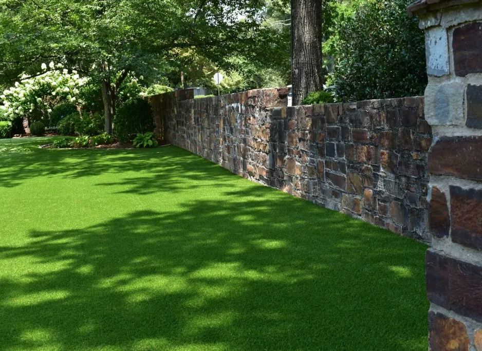 A stone wall surrounds a lush green lawn