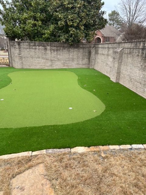 A putting green with a brick wall in the background