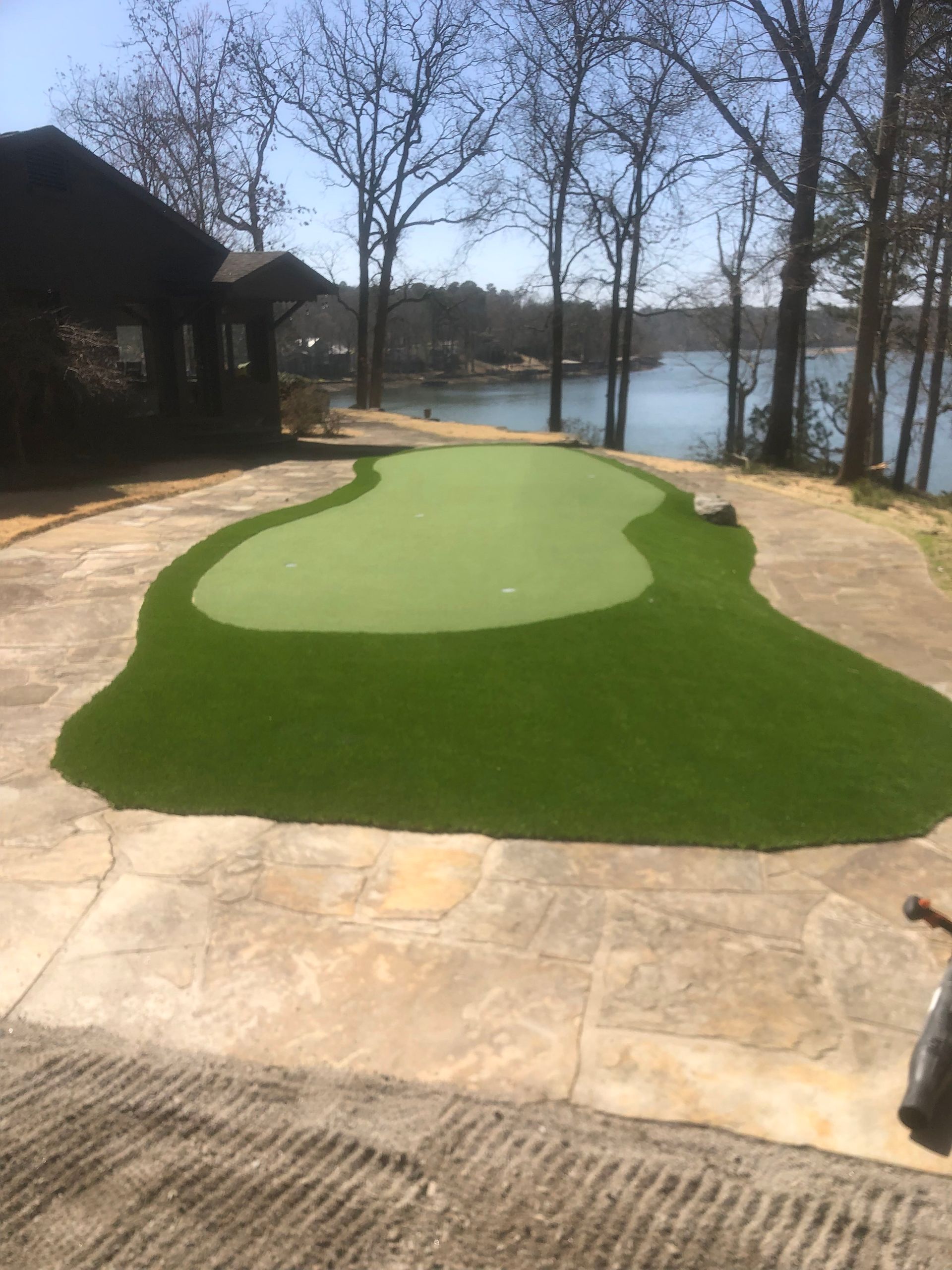 A golf course with a house in the background and a lake in the background.