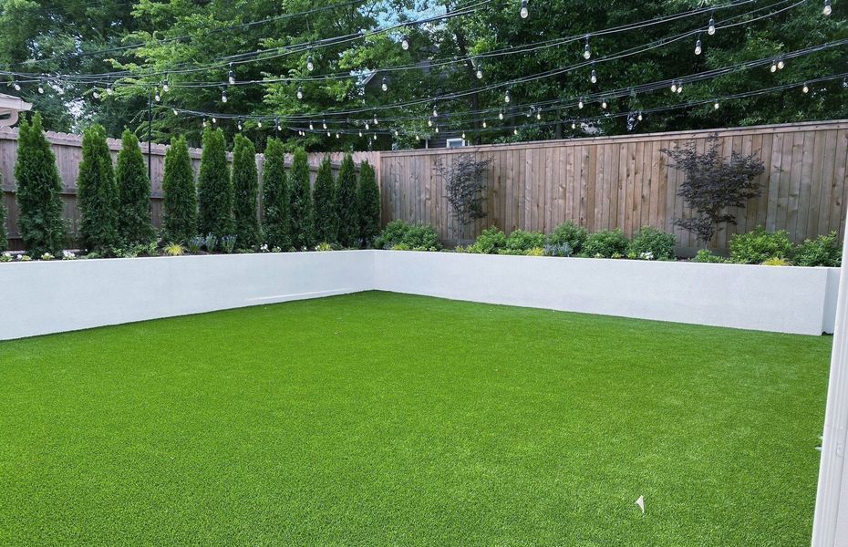 A backyard with a lush green lawn and a wooden fence.