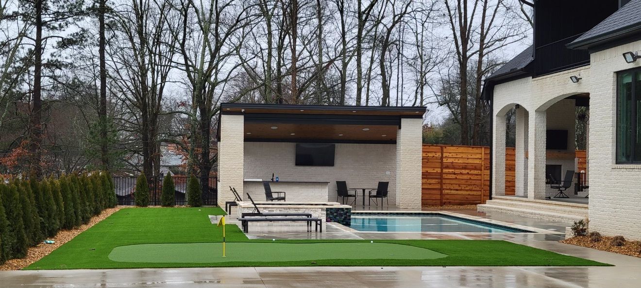 A backyard with a swimming pool and a putting green.