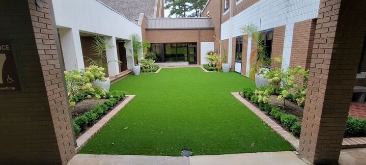 There is a large lawn in the middle of a courtyard between two buildings.