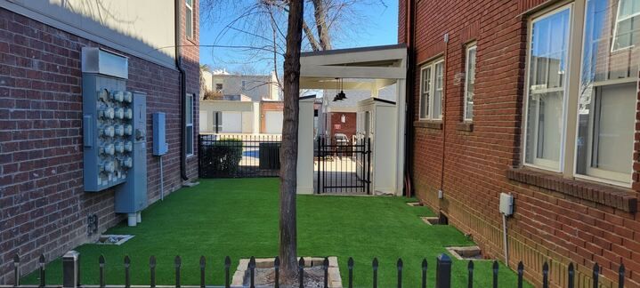 A brick building with a fence and a tree in the backyard.