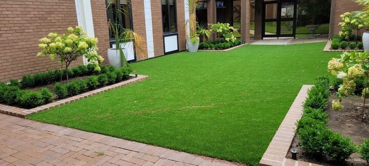 A brick building with a lush green lawn in front of it.