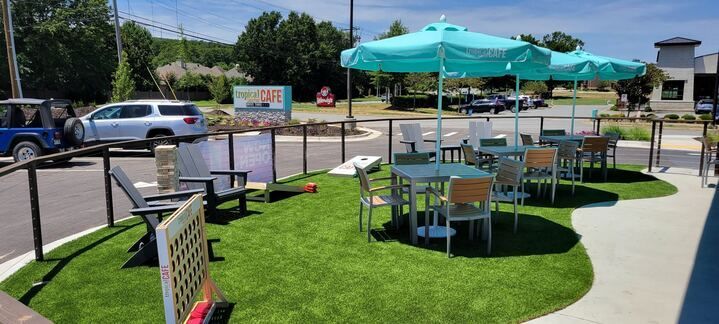 A patio area with tables and chairs and umbrellas.