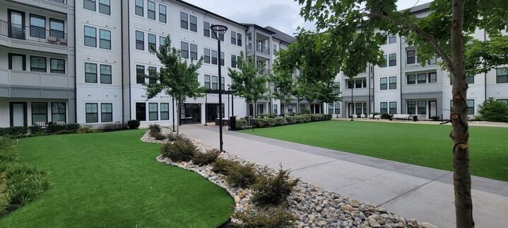 A large apartment building with a large lawn in front of it.