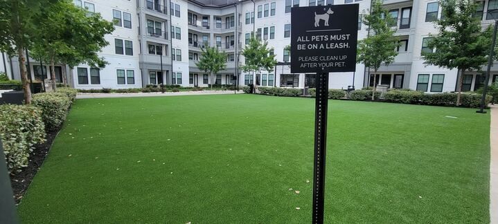 A dog park with a sign that says `` no pets must be on a leash '' in front of a building.