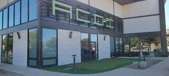 A large building with a lot of windows and a lawn in front of it.