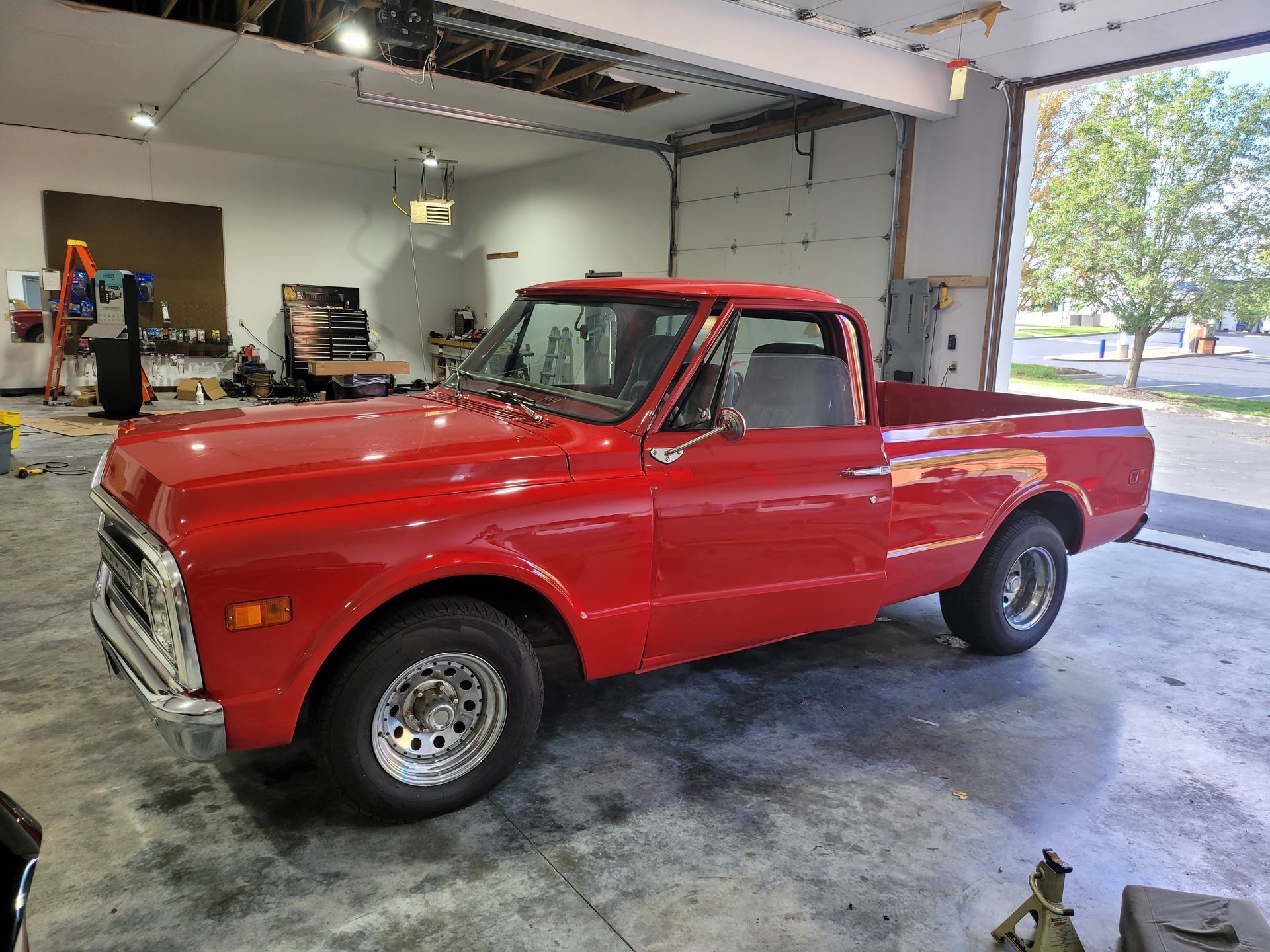 A red truck is parked in a garage with the door open.