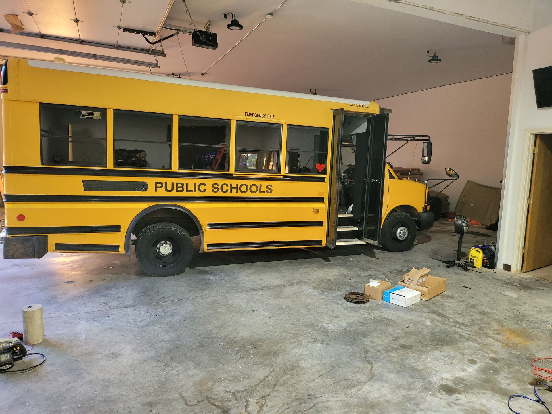 A yellow school bus is parked in a garage.