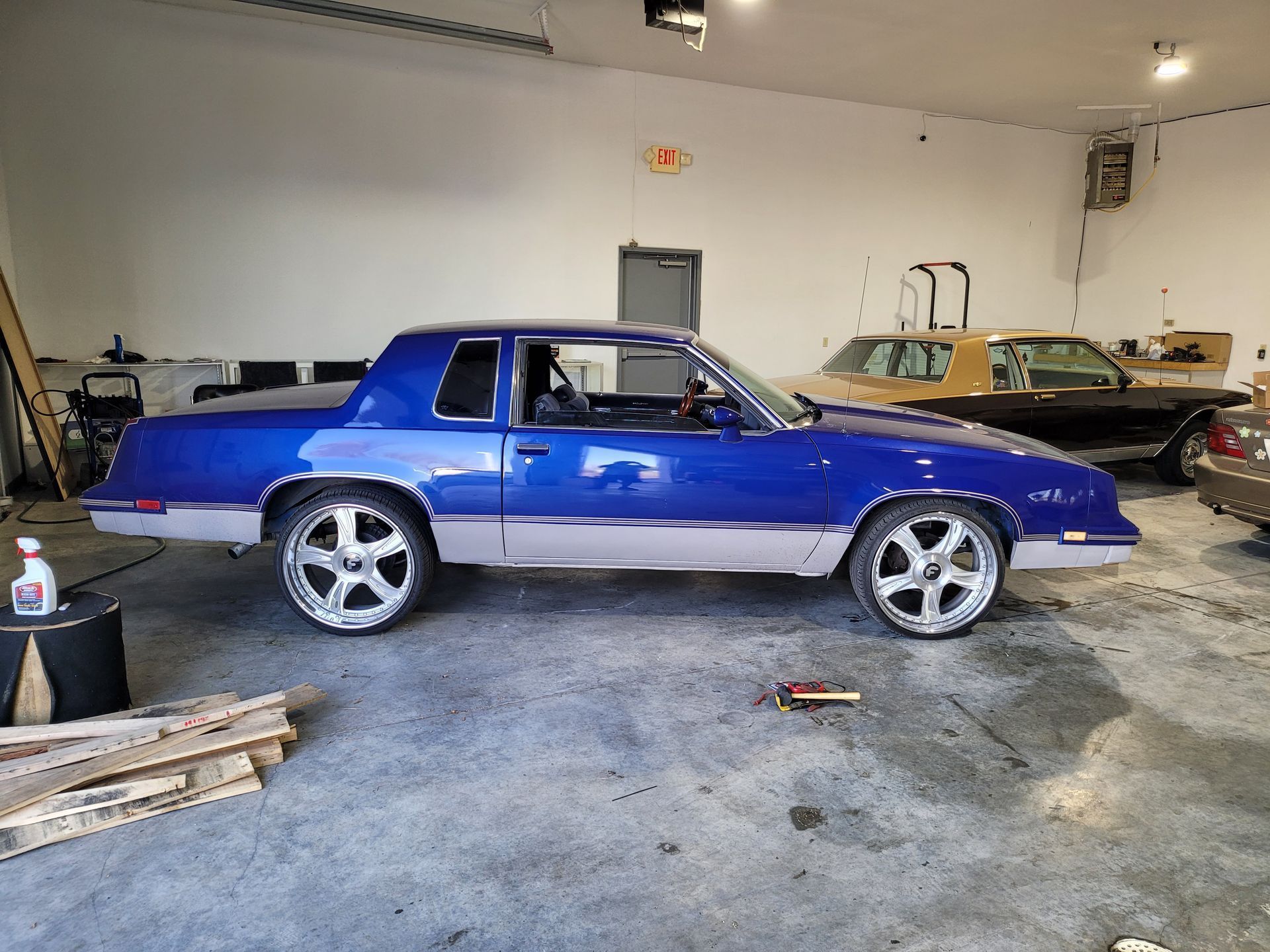 A blue car is parked in a garage next to other cars.