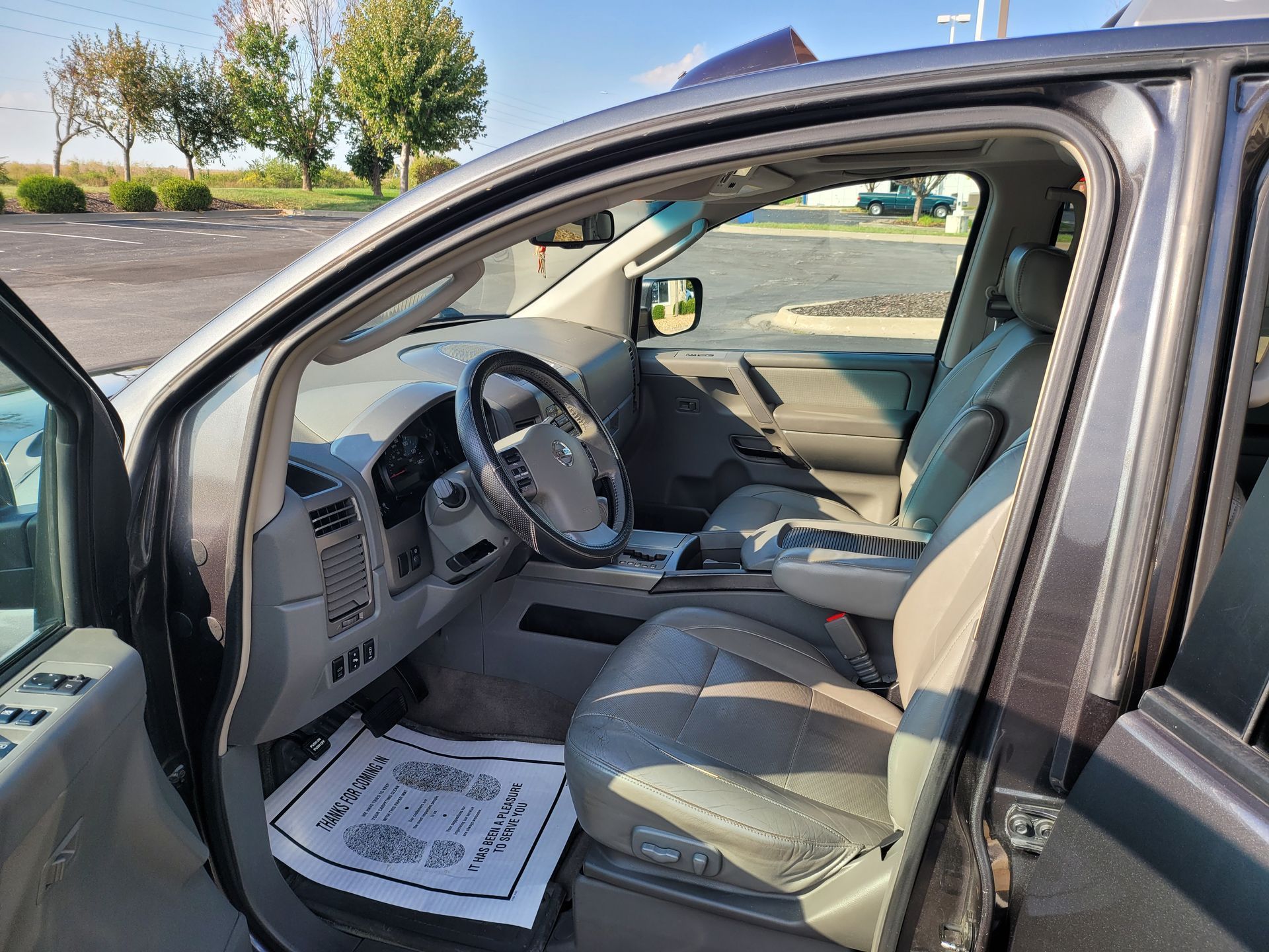 The inside of a car with the door open and a steering wheel.
