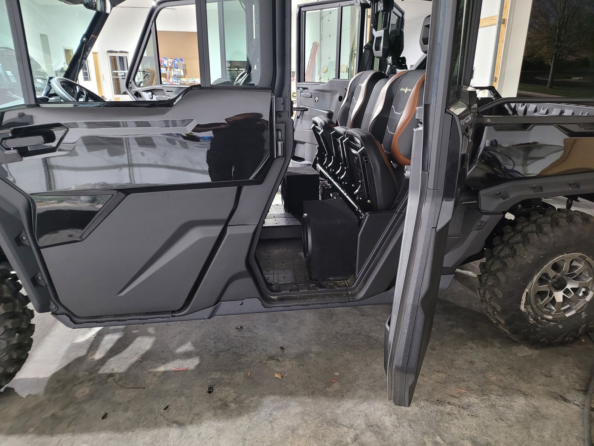 A black utility vehicle is parked in a garage with the door open.