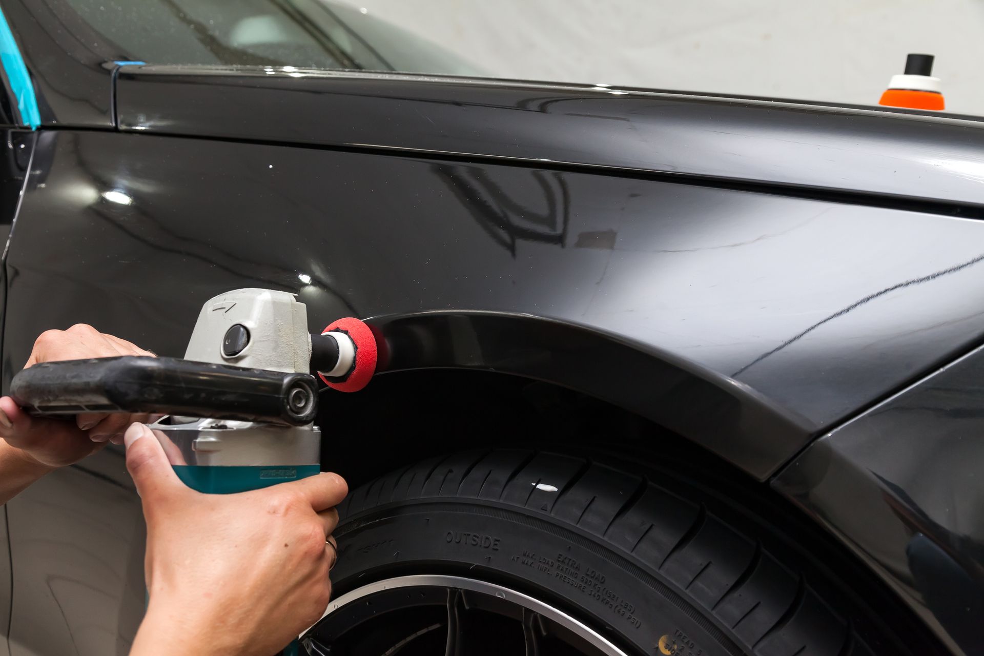A person is polishing the fender of a black car
