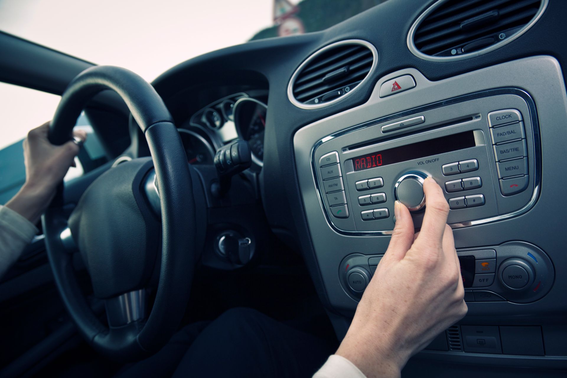 A person is adjusting the radio in a car