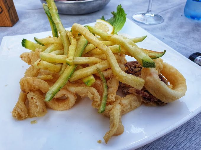 Un piatto di cibo con patatine fritte e zucchine su un tavolo.