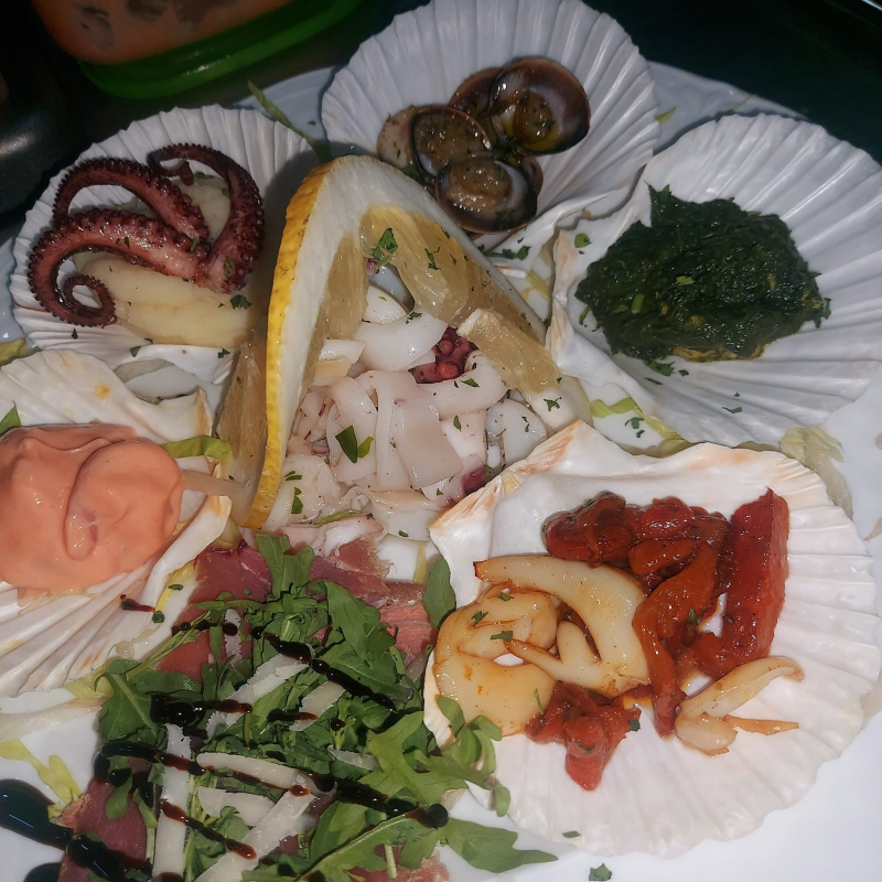 Un piatto bianco guarnito con una varietà di frutti di mare e verdure