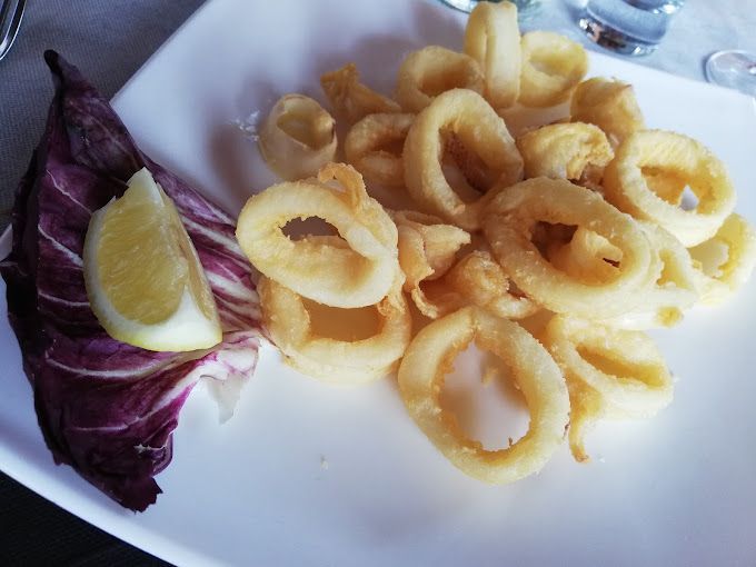 Un piatto bianco condito con calamari fritti e lattuga