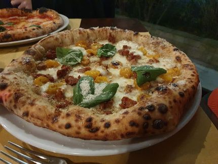 Una pizza su un piatto bianco con una forchetta su un tavolo.