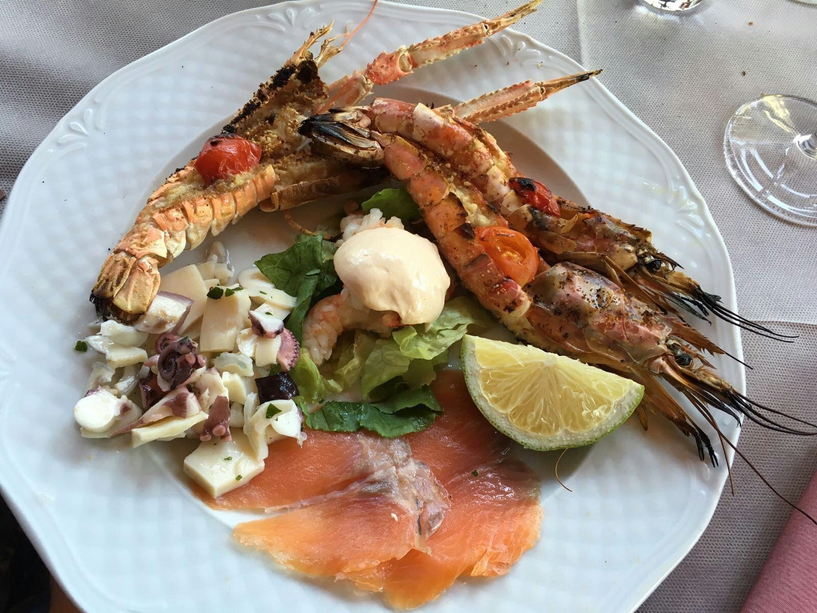 Un piatto bianco condito con gamberi e salmone affumicato