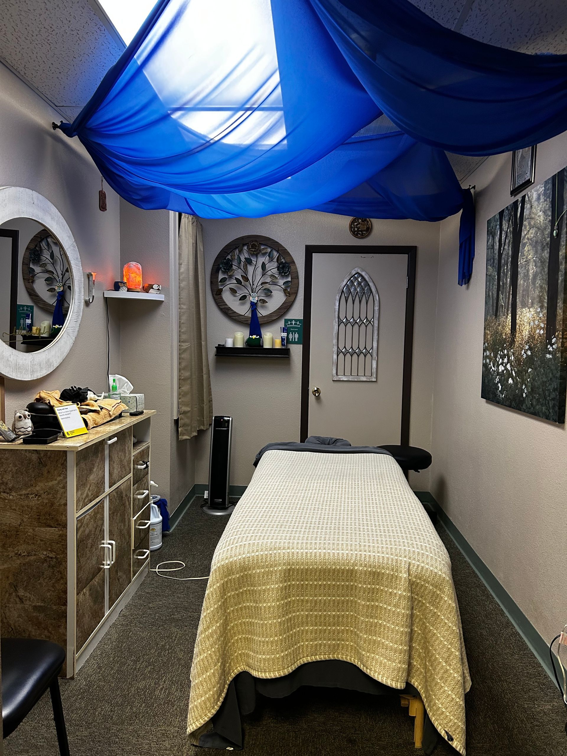 A massage table in a room with a blue curtain hanging from the ceiling.