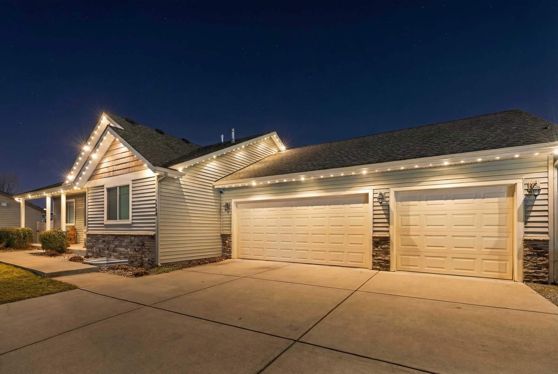 Suburban house exterior at night with lit garage and driveway