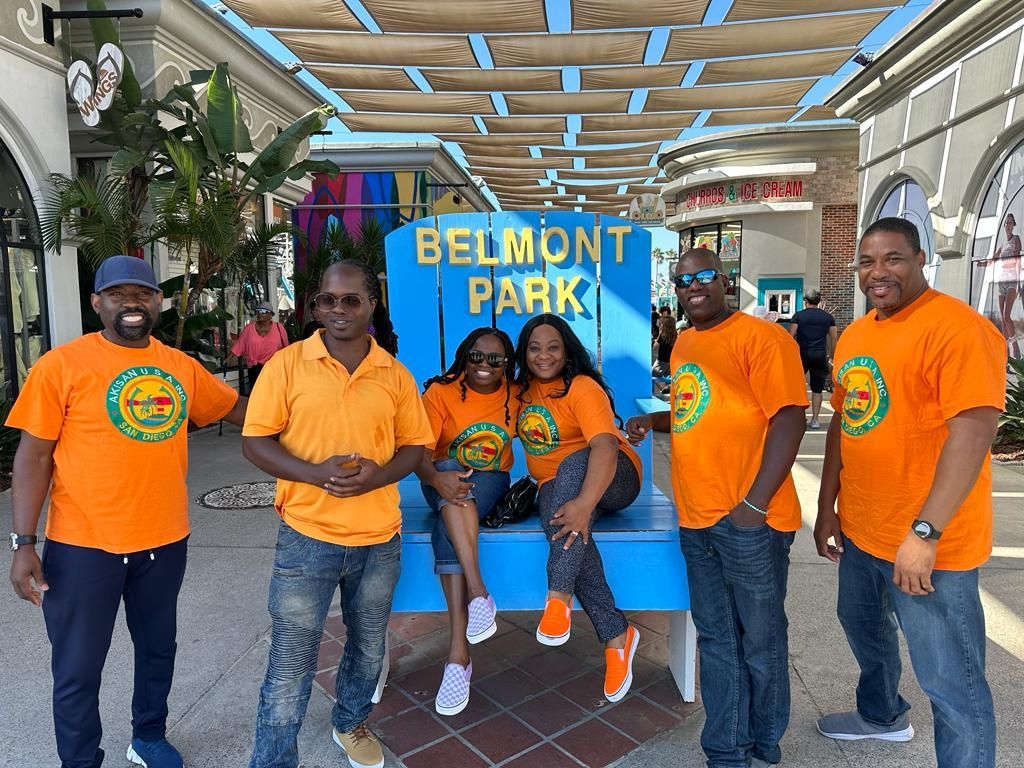 A group of people are posing for a picture in front of a belmont park sign.
