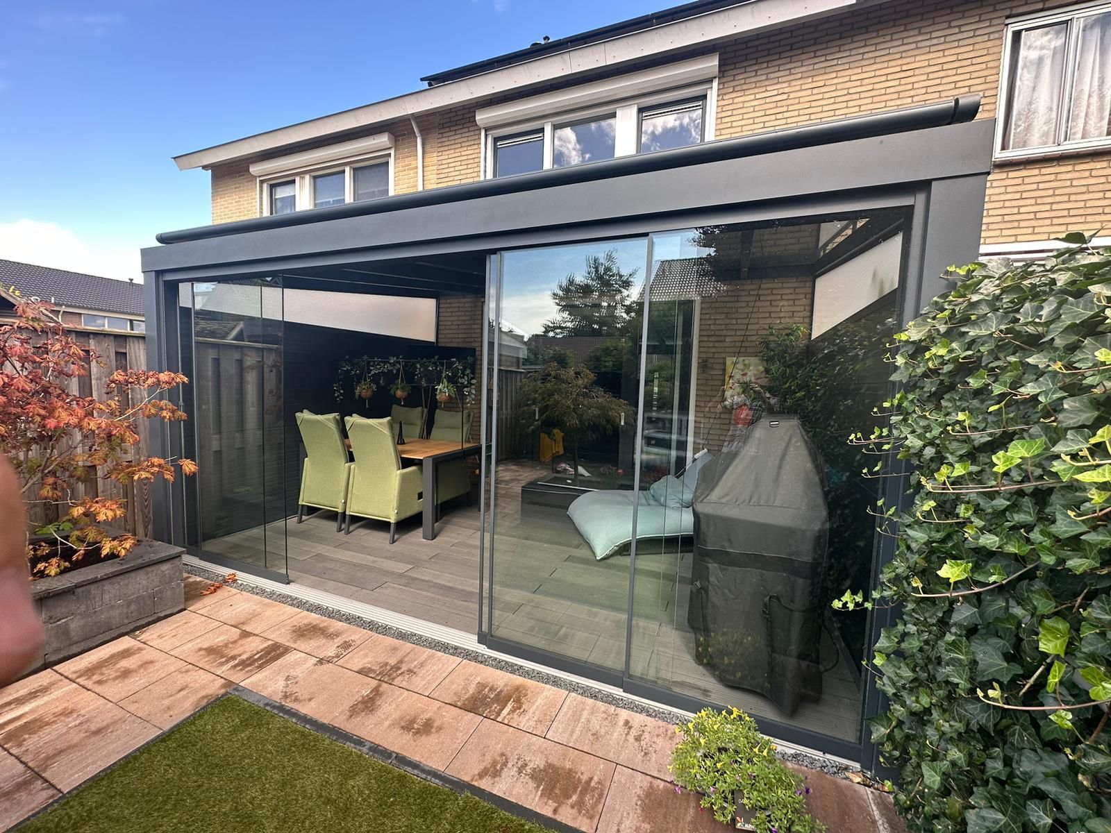 Een huis met een terras met glazen schuifdeuren en een tafel en stoelen.