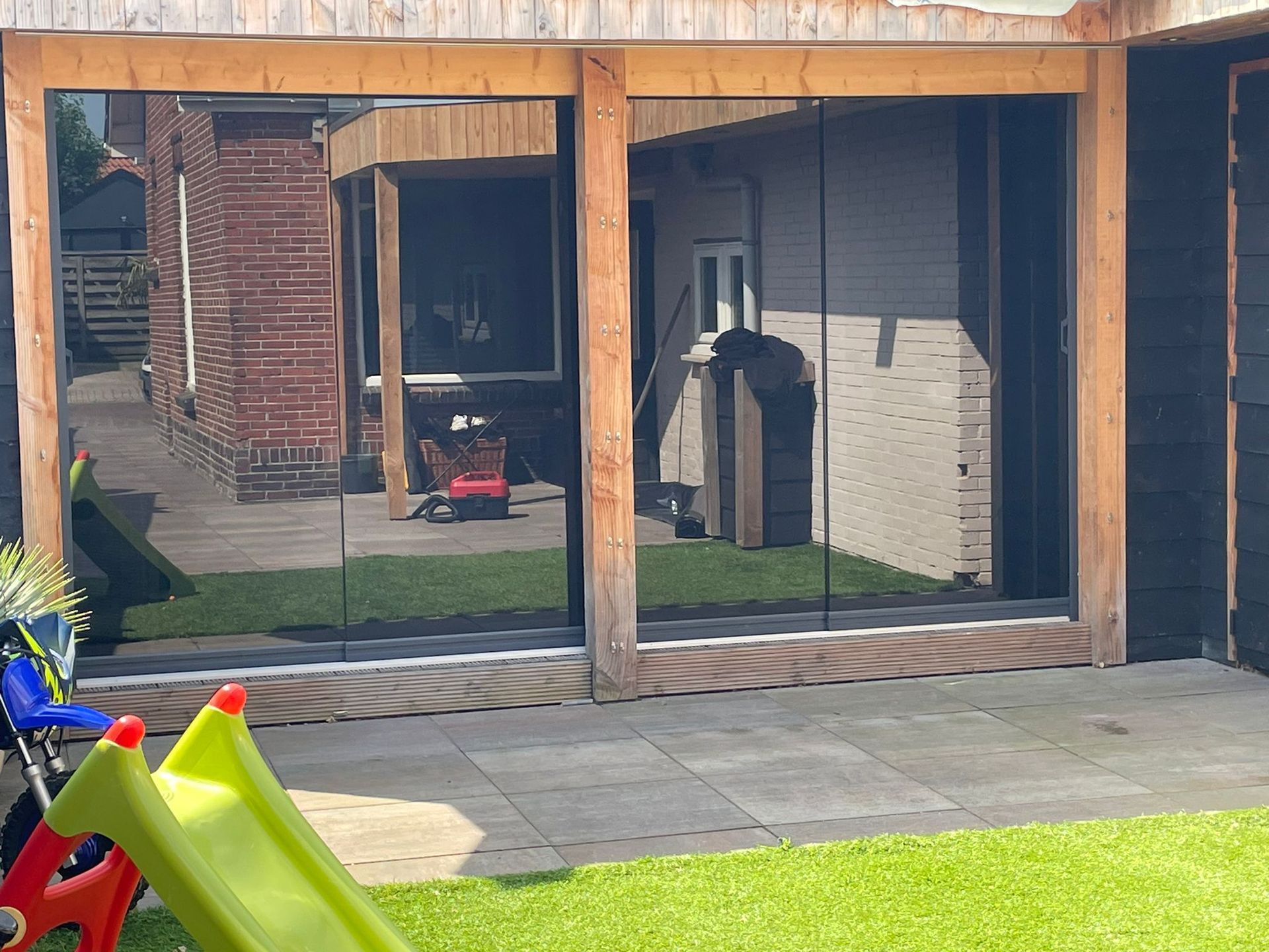 Een huis met glazen schuifdeuren en een glijbaan ervoor