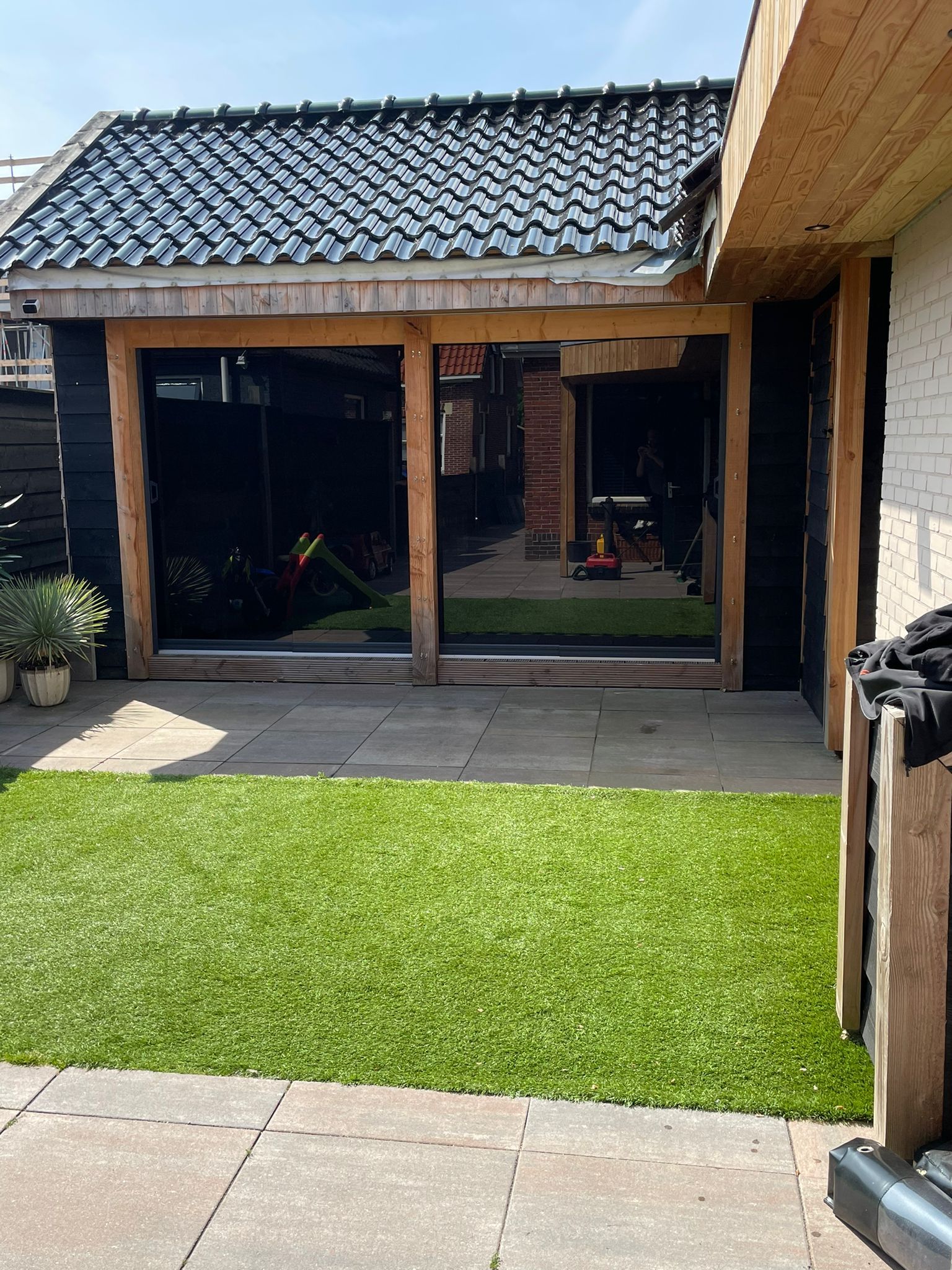 Een huis met een grote glazen schuifdeur en een weelderig groen gazon ervoor.