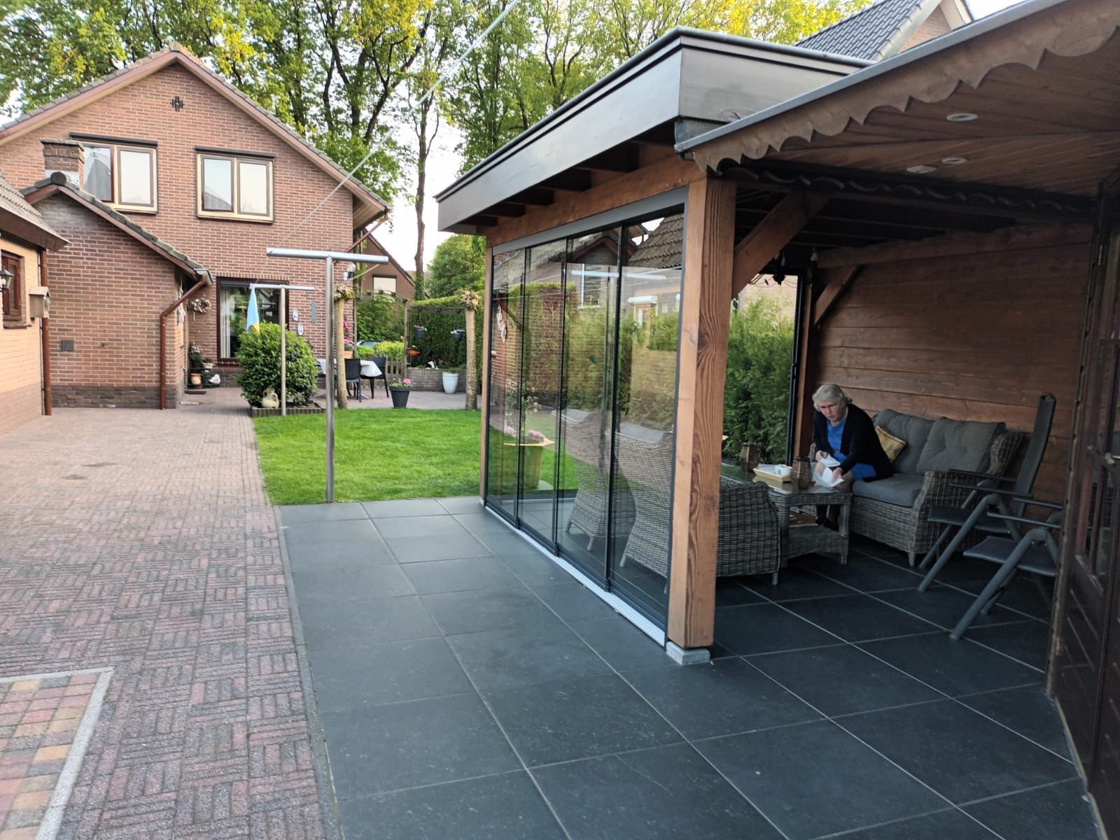Een man zit op een terras voor een huis.