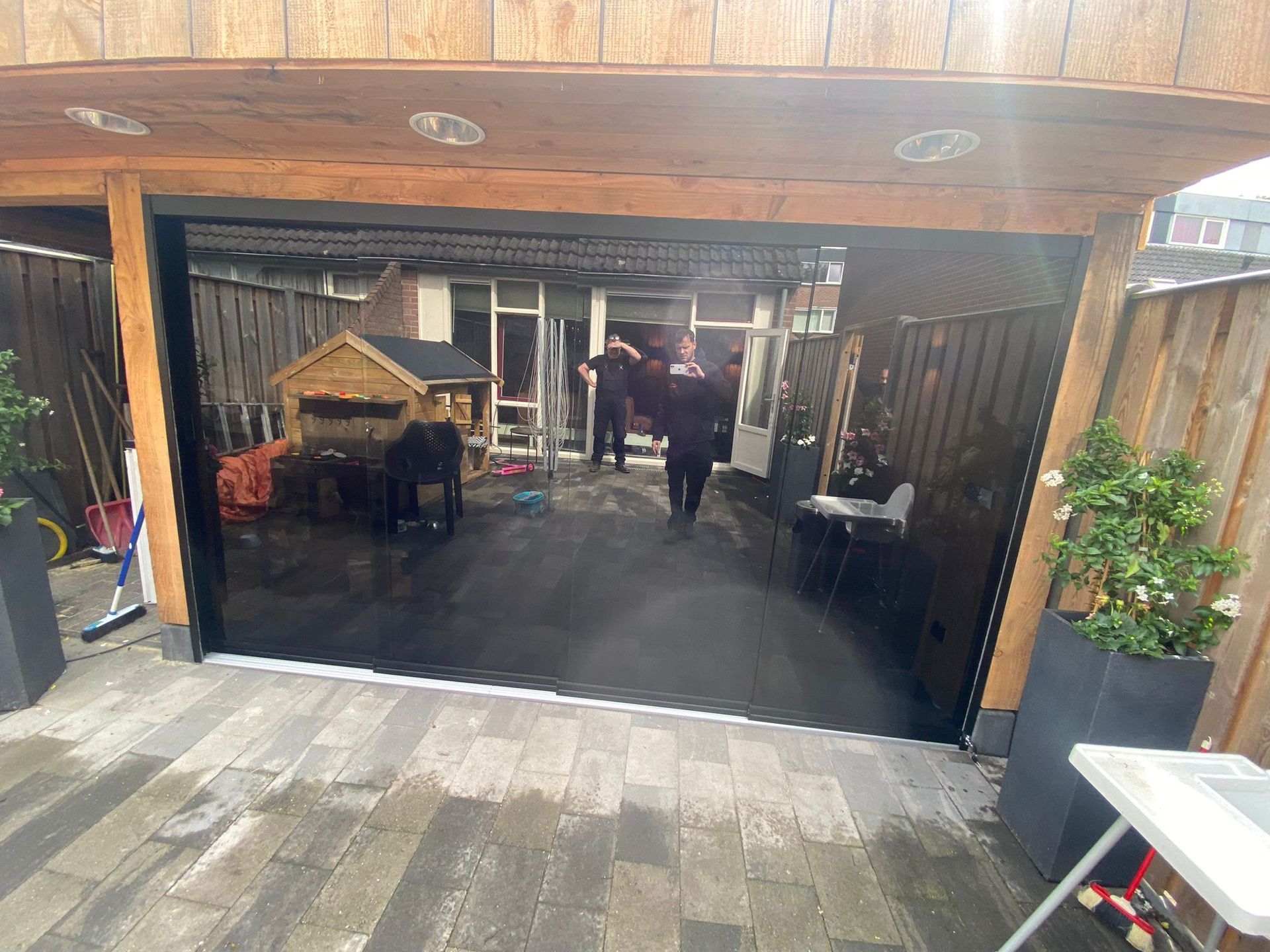 Een groep mensen staat buiten een garagedeur.