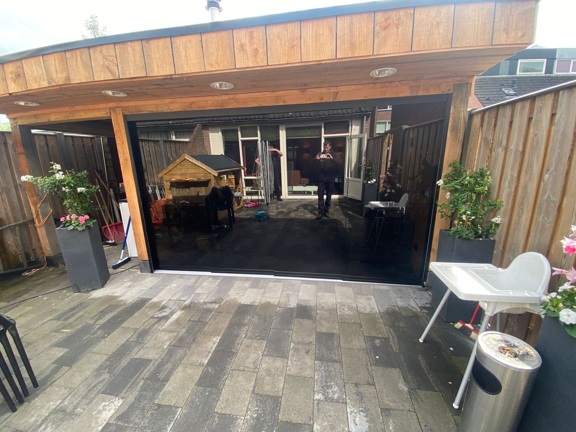 Een terras met een kinderstoel en een vuilnisbak voor een garagedeur.