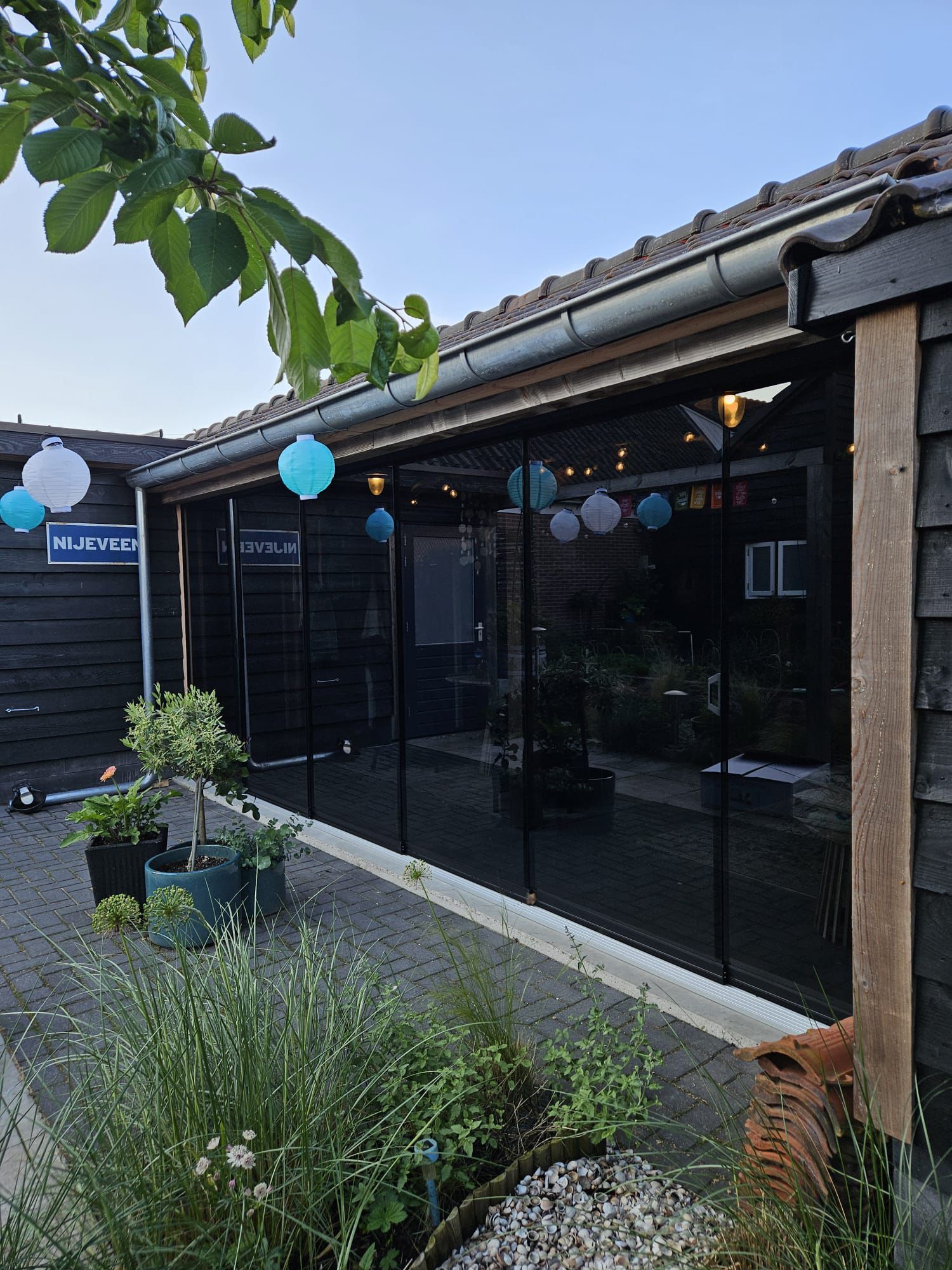 Een huis met veel ramen en planten ervoor.
