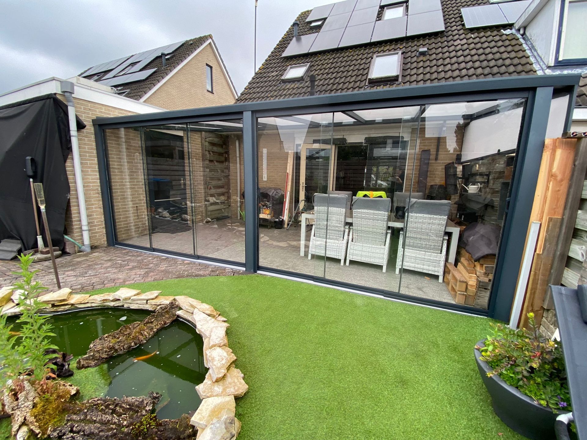 Een terras met een tafel en stoelen en een vijver voor een huis.