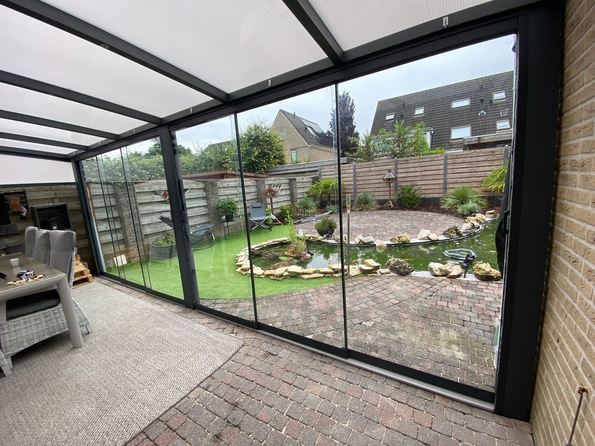 Een kamer met veel ramen en een vijver op de achtergrond.