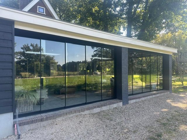 Een groot gebouw met veel ramen en bomen op de achtergrond.